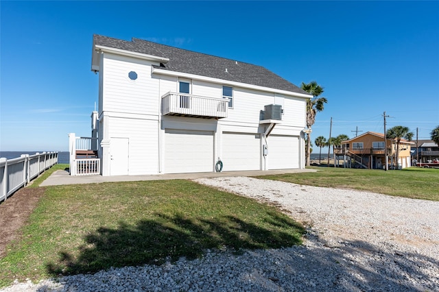 rear view of property featuring a lawn, a balcony, and a garage