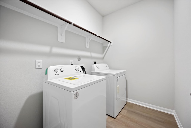 washroom featuring washing machine and dryer and light hardwood / wood-style flooring