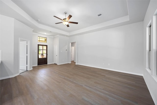 unfurnished room with a raised ceiling, ceiling fan, and dark wood-type flooring