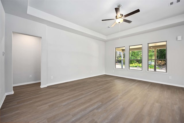 unfurnished room featuring ceiling fan, a raised ceiling, and dark wood-type flooring