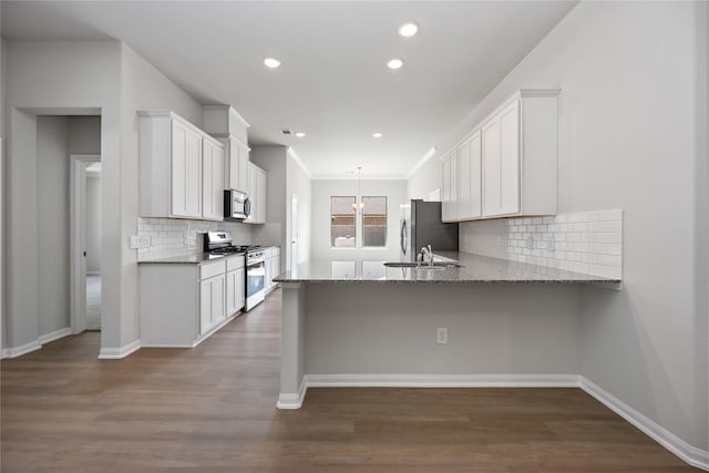 kitchen featuring light stone countertops, backsplash, wood-type flooring, white cabinets, and appliances with stainless steel finishes