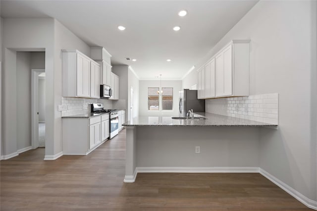 1485 Rd 66114, Dayton, TX 77535 - kitchen featuring stainless steel appliances, a sink, a peninsula, light stone countertops, and white cabinetry