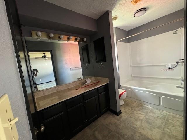 full bathroom featuring vanity, ceiling fan, toilet, a textured ceiling, and shower / bath combination