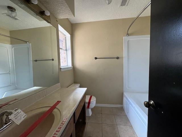 full bathroom featuring tile patterned floors, vanity, a textured ceiling, and toilet