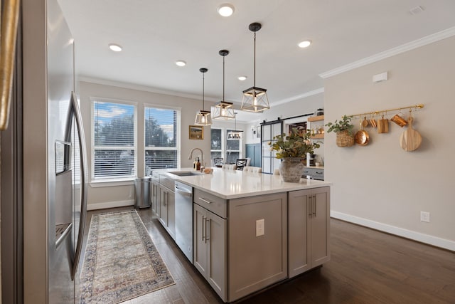 kitchen featuring sink, stainless steel appliances, a barn door, dark hardwood / wood-style flooring, and a kitchen island with sink