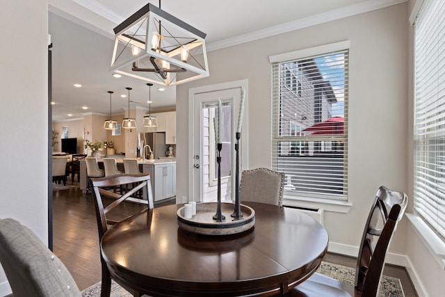 dining room featuring crown molding, sink, dark wood-type flooring, and a notable chandelier