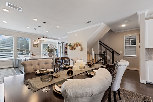 dining space featuring sink, a barn door, crown molding, and dark wood-type flooring