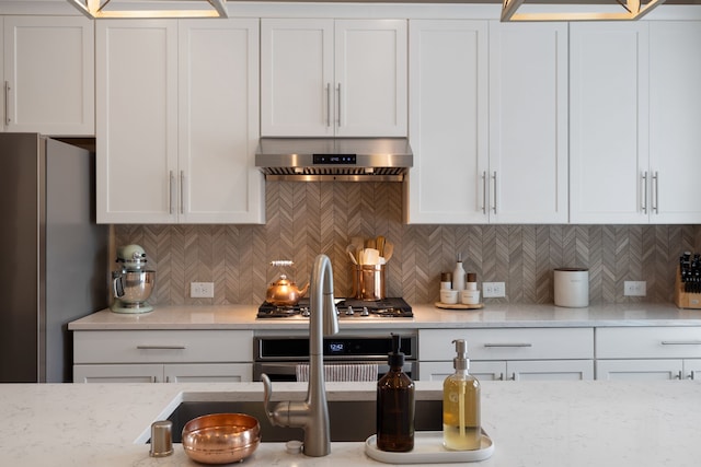 kitchen with appliances with stainless steel finishes, white cabinetry, and extractor fan