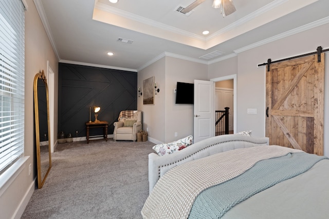 carpeted bedroom featuring a barn door, a tray ceiling, ceiling fan, and ornamental molding