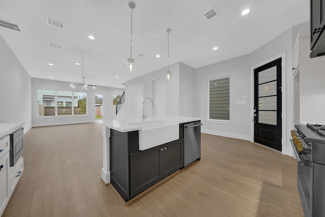 kitchen featuring decorative light fixtures, sink, stainless steel appliances, and an island with sink