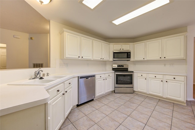 kitchen with sink, light tile patterned floors, white cabinetry, kitchen peninsula, and stainless steel appliances