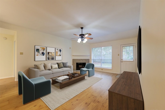 living room with hardwood / wood-style flooring, ceiling fan, and a tiled fireplace