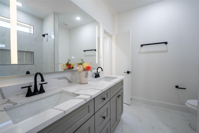 bathroom with vanity, toilet, and tiled shower