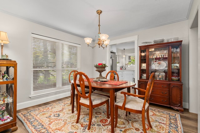 dining room with ornamental molding, wood-type flooring, and an inviting chandelier