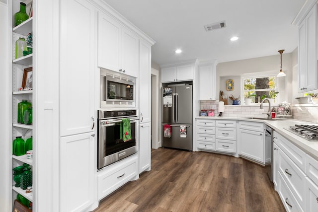 kitchen featuring hanging light fixtures, sink, dark hardwood / wood-style floors, appliances with stainless steel finishes, and white cabinetry