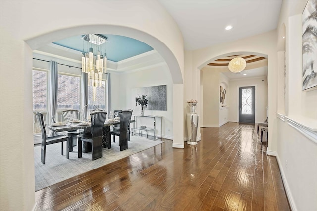 dining space with a tray ceiling, crown molding, a chandelier, and dark hardwood / wood-style floors