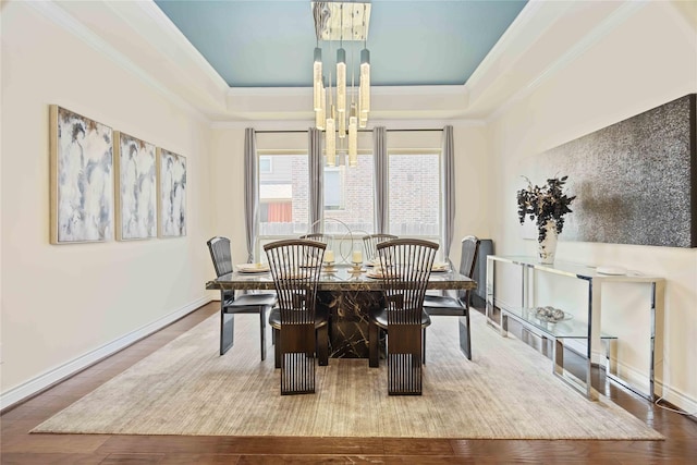 dining space with hardwood / wood-style floors, a tray ceiling, and crown molding