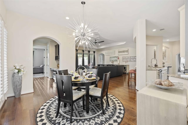 dining room with a notable chandelier, dark wood-type flooring, and sink