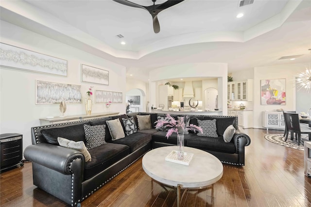 living room featuring hardwood / wood-style flooring, ceiling fan, and a tray ceiling