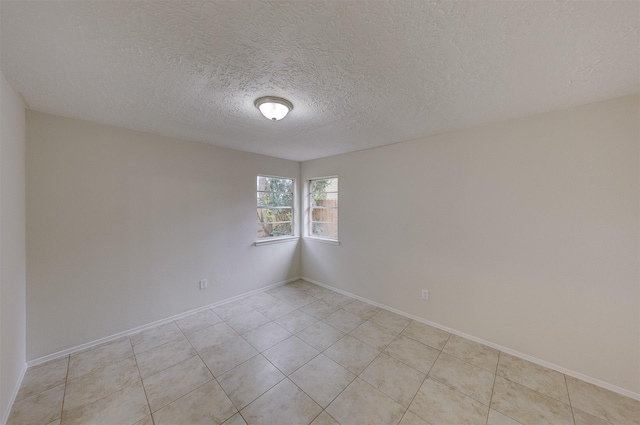 empty room with light tile patterned flooring and a textured ceiling