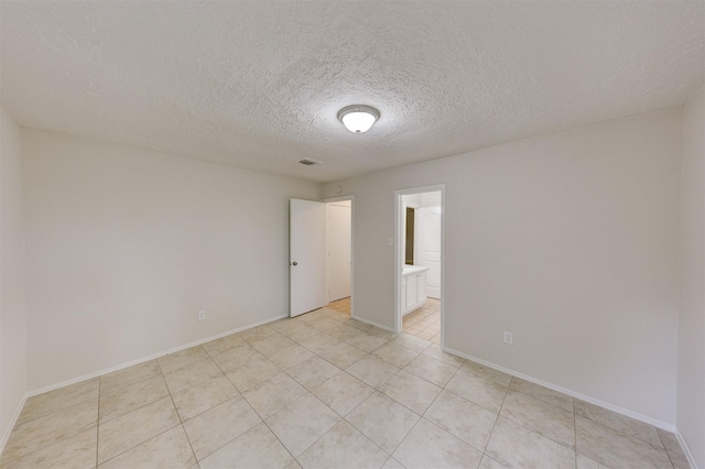 empty room featuring light tile patterned flooring and a textured ceiling