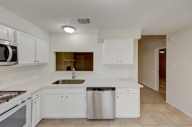 kitchen featuring decorative backsplash, appliances with stainless steel finishes, white cabinetry, and sink