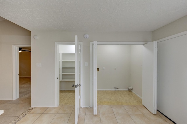 laundry area with light tile patterned floors and a textured ceiling