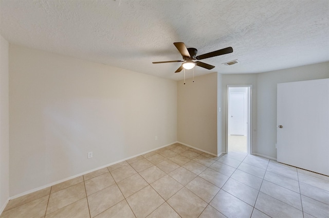 spare room featuring ceiling fan, light tile patterned floors, and a textured ceiling