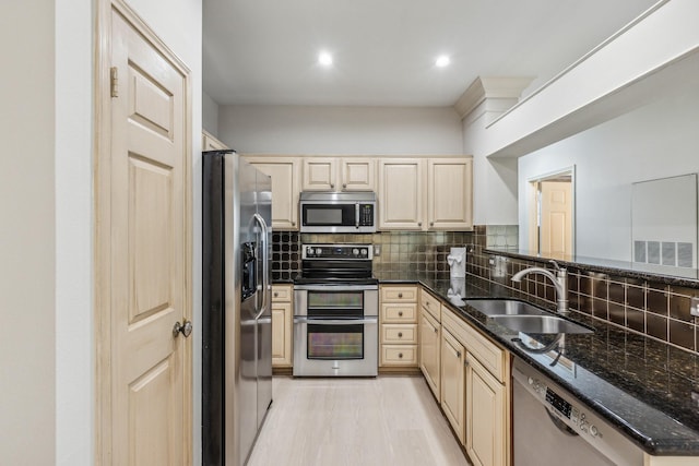 kitchen featuring sink, dark stone countertops, decorative backsplash, appliances with stainless steel finishes, and light wood-type flooring