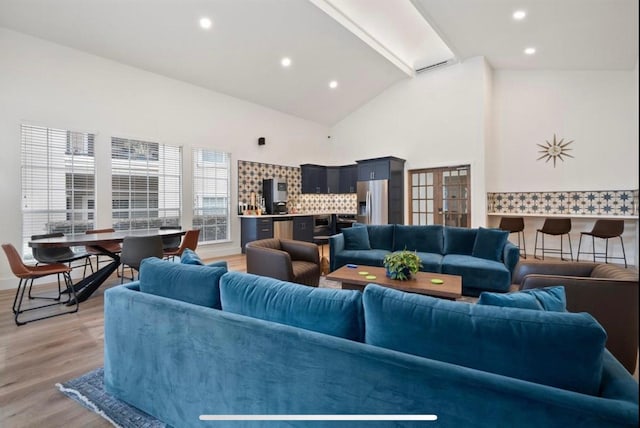 living room with light wood-type flooring and high vaulted ceiling