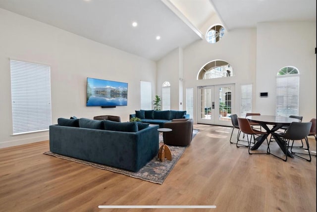 living room featuring light hardwood / wood-style floors, high vaulted ceiling, and french doors