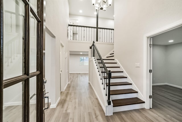 staircase with hardwood / wood-style flooring, a notable chandelier, and a high ceiling