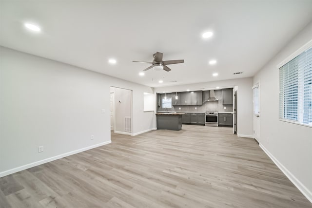 kitchen with wall chimney exhaust hood, light hardwood / wood-style floors, electric stove, and ceiling fan