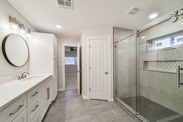 bathroom with vanity, ceiling fan, and a shower with shower door