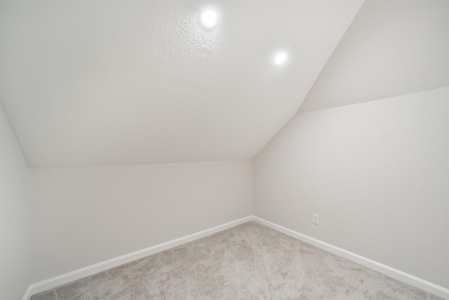 additional living space with light carpet and vaulted ceiling