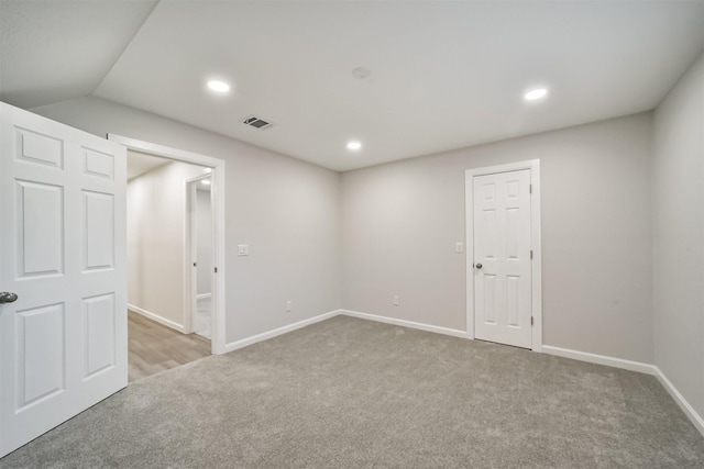 empty room featuring light colored carpet and vaulted ceiling