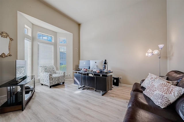 office area featuring a towering ceiling and light hardwood / wood-style flooring