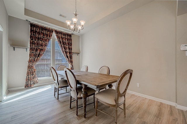 dining space featuring light wood-type flooring and a notable chandelier