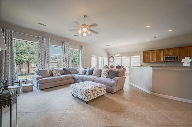 living room with ceiling fan, lofted ceiling, and light tile patterned floors