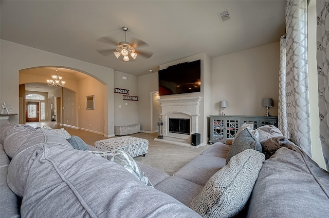 tiled living room featuring ceiling fan with notable chandelier