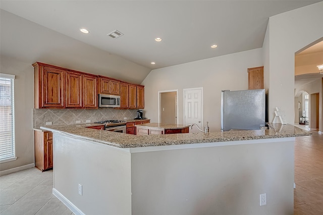 kitchen with stainless steel appliances, a kitchen island, backsplash, lofted ceiling, and light tile patterned floors