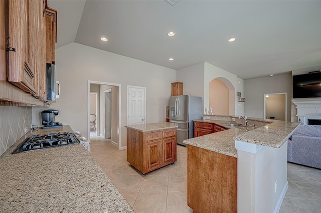 kitchen featuring light stone countertops, appliances with stainless steel finishes, sink, a center island with sink, and lofted ceiling