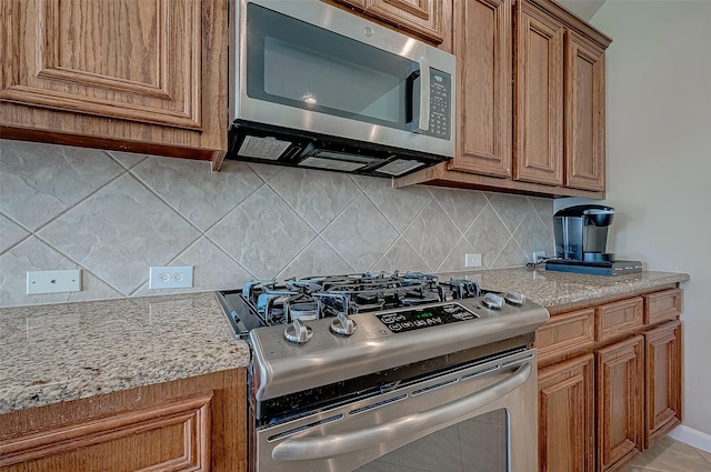 kitchen with light stone countertops, backsplash, and stainless steel appliances