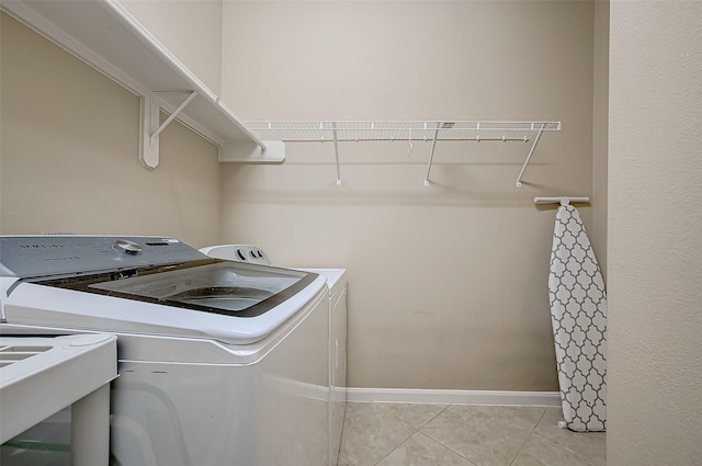 laundry area with separate washer and dryer, sink, and light tile patterned flooring