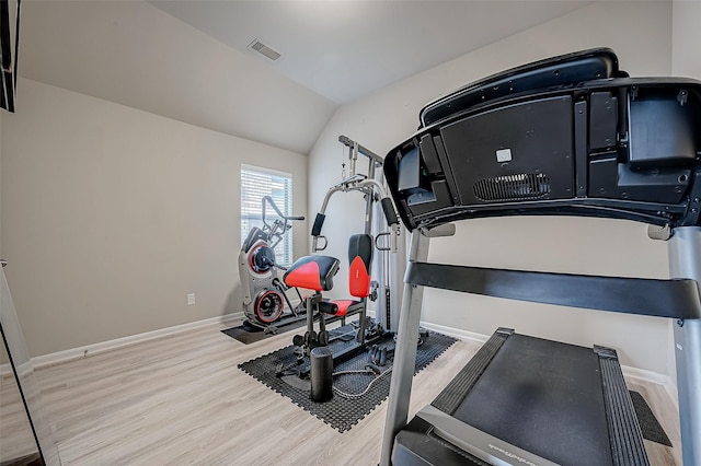 exercise room featuring light hardwood / wood-style flooring and vaulted ceiling