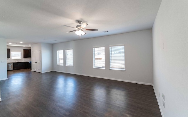 unfurnished living room with dark wood-style floors, ceiling fan, visible vents, and baseboards