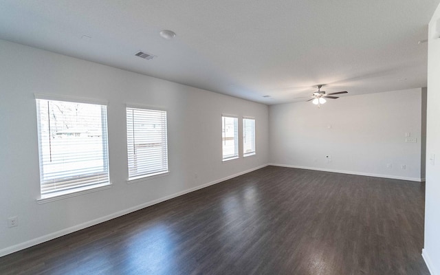 spare room featuring baseboards, visible vents, and dark wood-type flooring