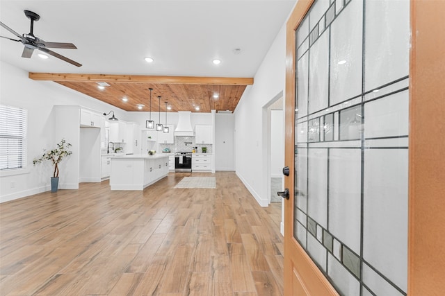 kitchen with white cabinets, light wood-type flooring, and custom range hood