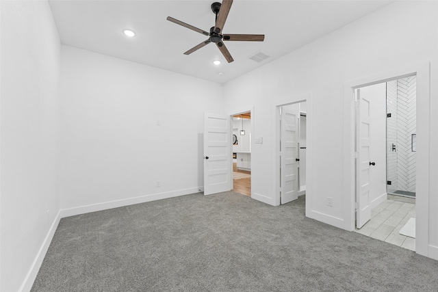 unfurnished bedroom with ceiling fan, light colored carpet, a walk in closet, and connected bathroom