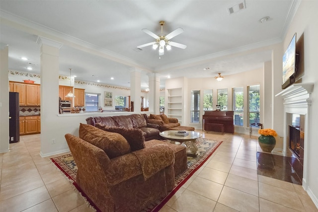 tiled living room with decorative columns, crown molding, built in features, and ceiling fan